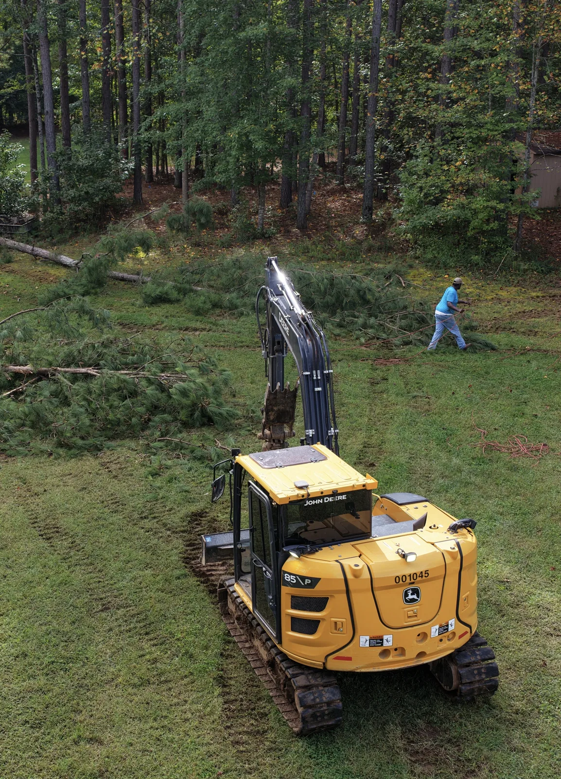 Excavator on cleared ground next to felled pines after land clearing in Mooresville, NC