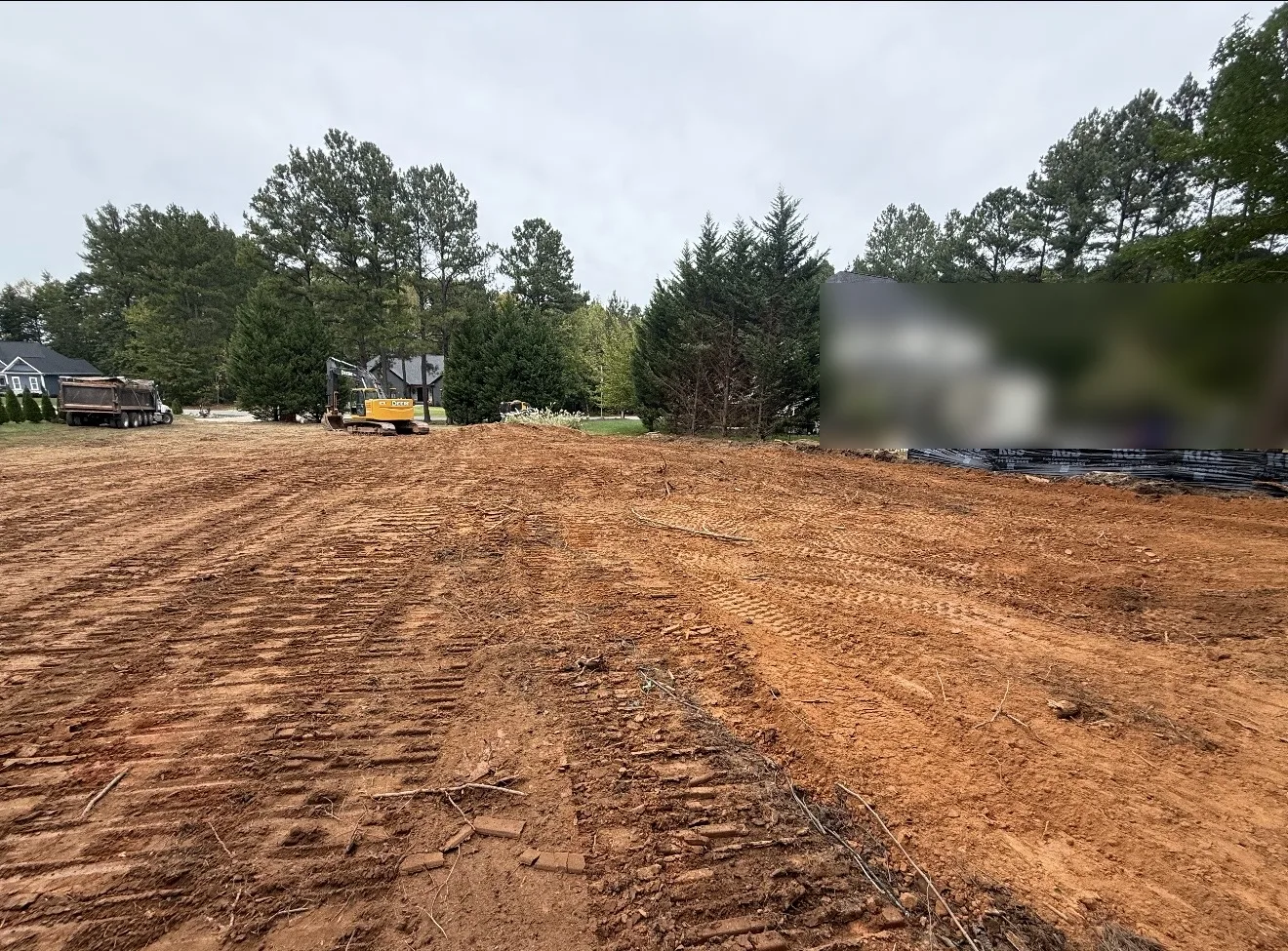 Lot cleared down to red dirt with equipment and silt fence after site prep in Mooresville, NC