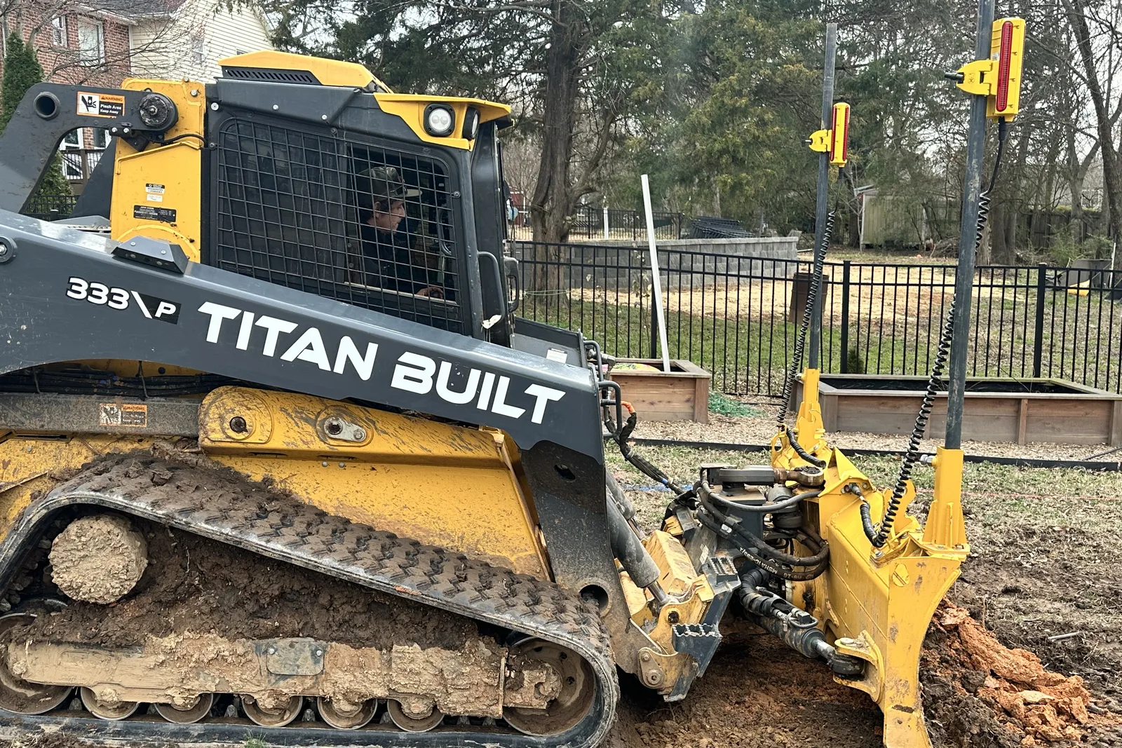 Titan Built Deere 333P with laser-guided grading attachment leveling a backyard in the Charlotte area