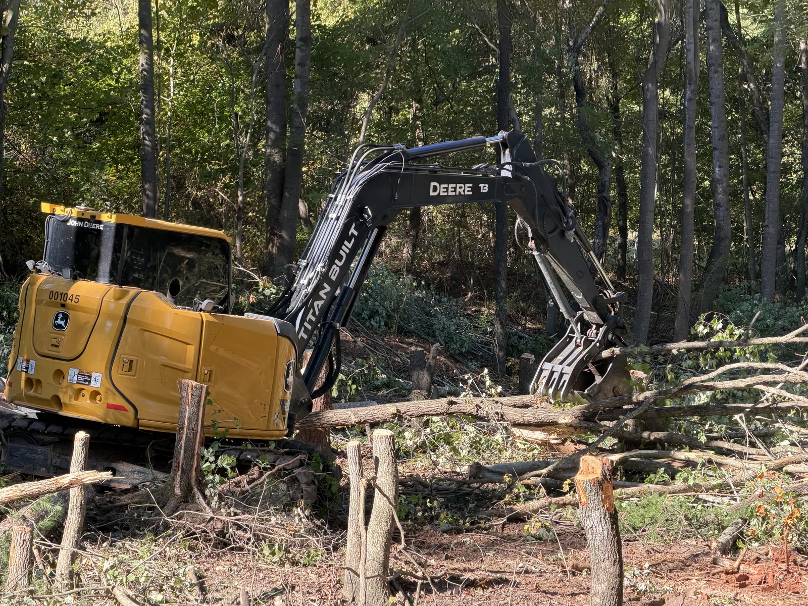 Titan Built excavator with thumb moving cleared timber on a wooded lot in Troutman, NC