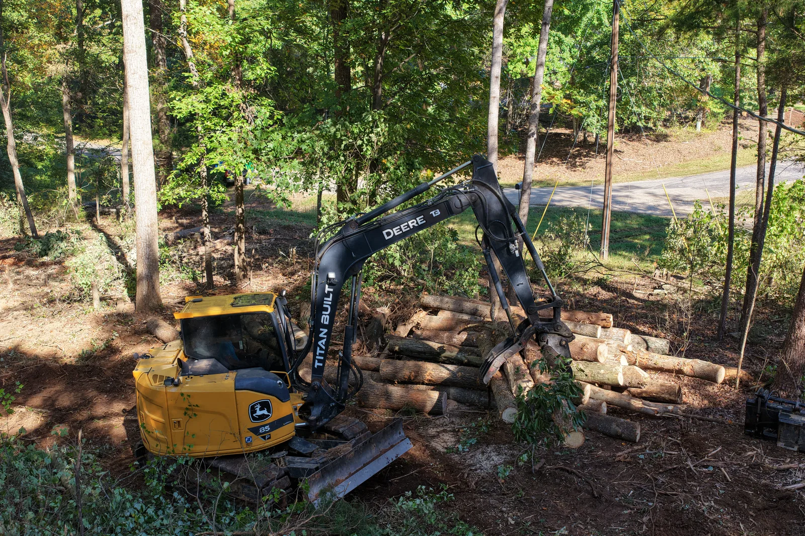 John Deere 85G excavator stacking cut logs into a pile while opening up a site in Troutman, NC